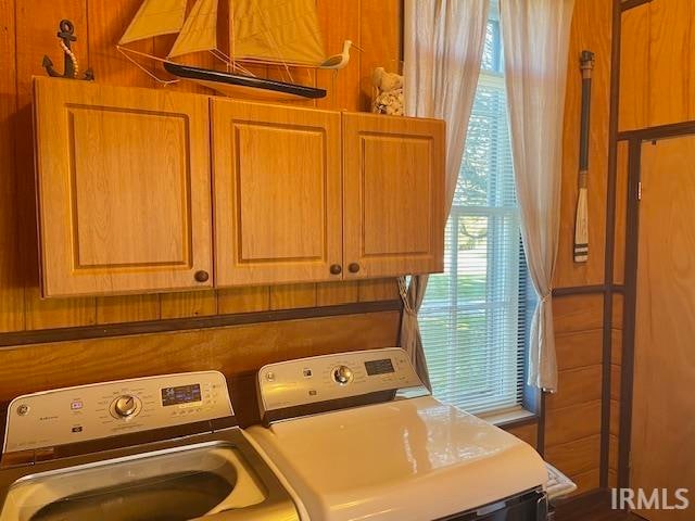 laundry room with independent washer and dryer, wood walls, and cabinets