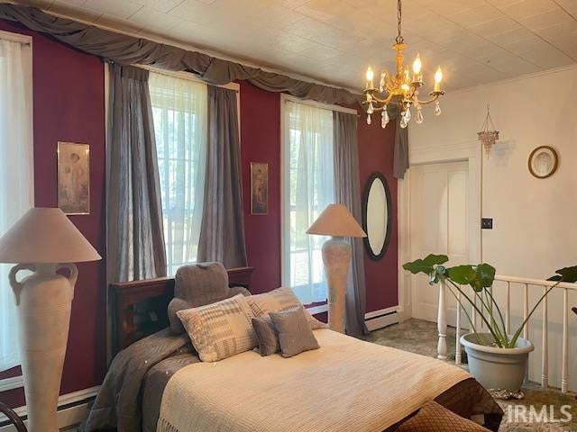 carpeted bedroom featuring a notable chandelier and a baseboard heating unit