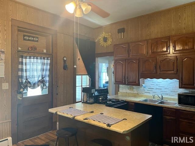 kitchen featuring a baseboard heating unit, wood walls, sink, and hardwood / wood-style floors