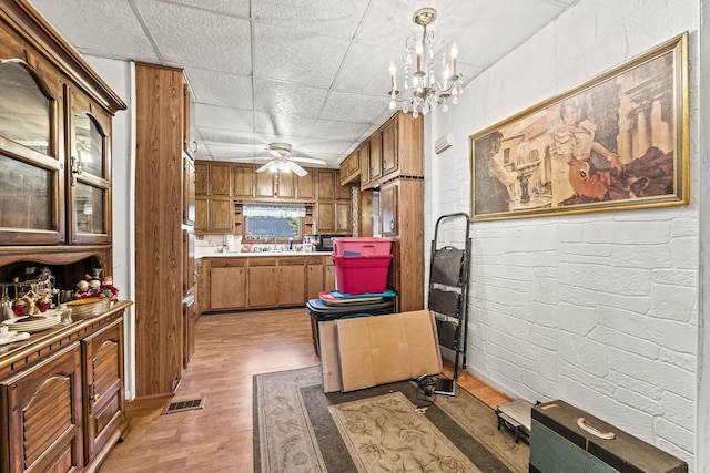 6885 N 315 E, Howe, IN 46746 - kitchen featuring visible vents, light wood-type flooring, brown cabinets, ceiling fan with notable chandelier, and hanging light fixtures
