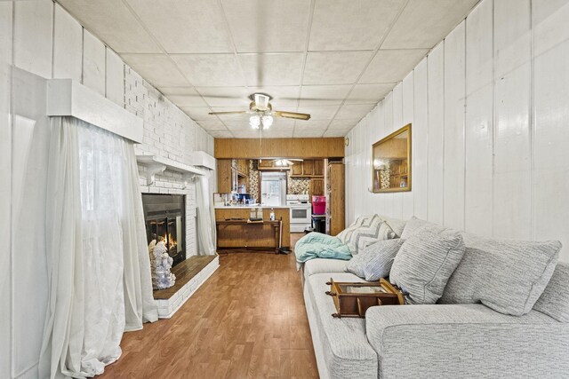 6885 N 315 E, Howe, IN 46746 - living area with wooden walls, a ceiling fan, wood finished floors, and a brick fireplace
