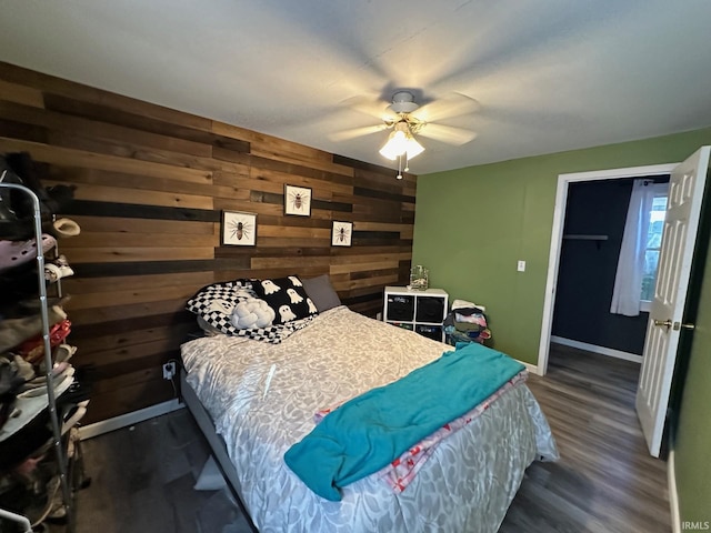 bedroom with dark hardwood / wood-style flooring, ceiling fan, and wooden walls