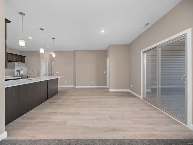 kitchen featuring dark brown cabinetry, pendant lighting, stainless steel refrigerator with ice dispenser, and light hardwood / wood-style flooring