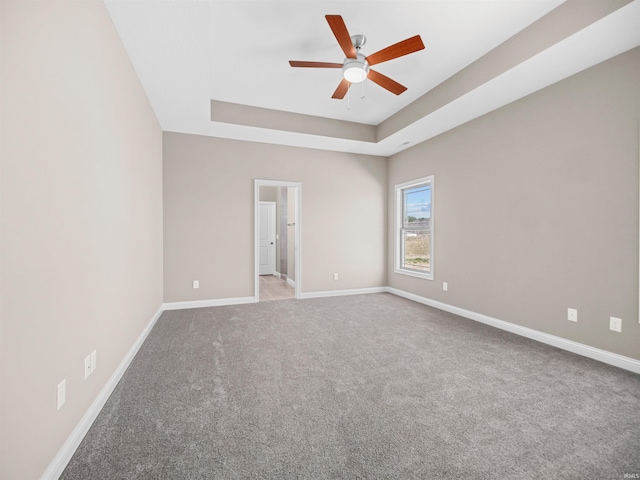 carpeted empty room with ceiling fan and a raised ceiling