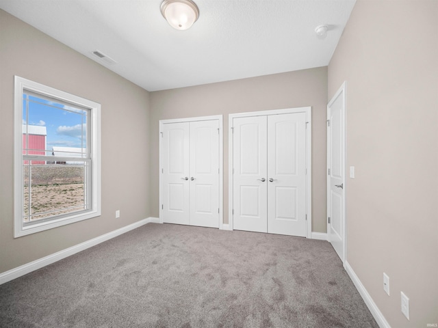 unfurnished bedroom with two closets and carpet