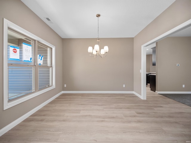 empty room featuring an inviting chandelier and light hardwood / wood-style floors