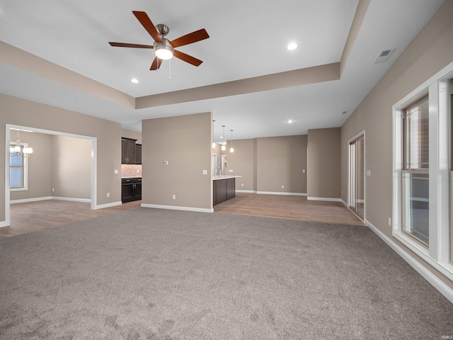 unfurnished living room featuring ceiling fan with notable chandelier and carpet flooring