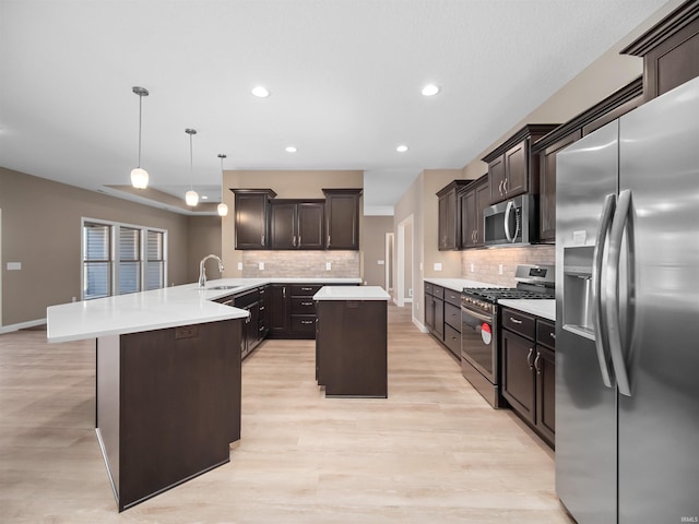 kitchen featuring light wood-type flooring, a kitchen island, decorative light fixtures, stainless steel appliances, and kitchen peninsula