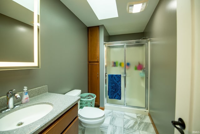 bathroom with a shower with door, a skylight, vanity, and toilet