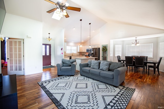 living room with ceiling fan with notable chandelier, dark hardwood / wood-style floors, and high vaulted ceiling