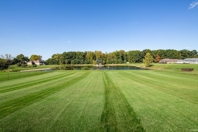 surrounding community with a water view and a yard