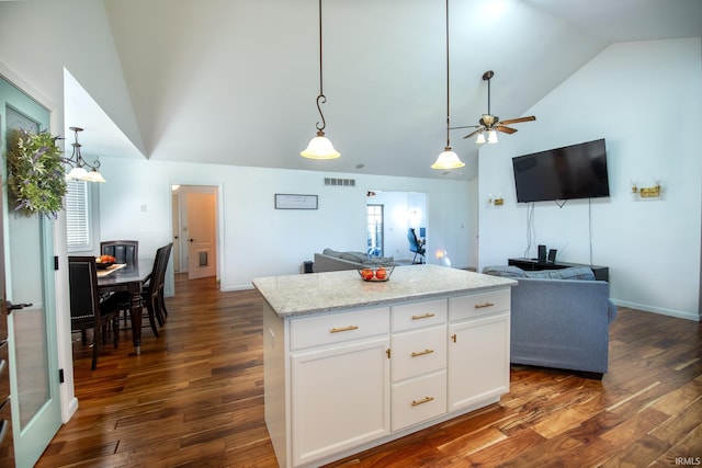 kitchen featuring decorative light fixtures, lofted ceiling, dark hardwood / wood-style floors, a center island, and white cabinetry