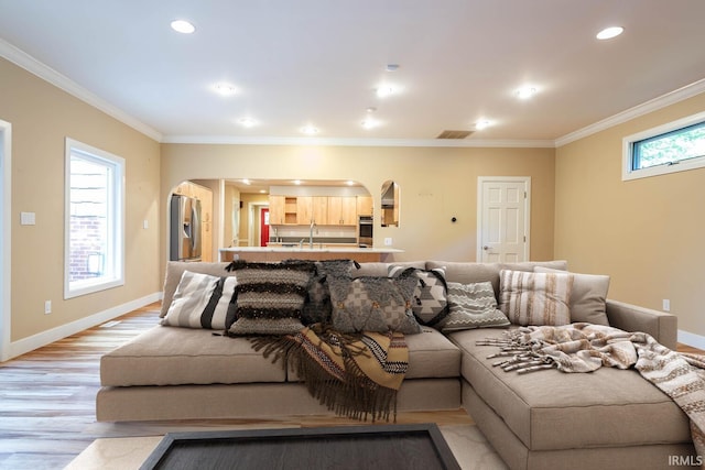 living room featuring crown molding, plenty of natural light, and light hardwood / wood-style floors