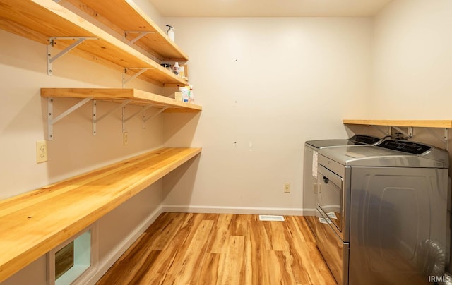 laundry room with light hardwood / wood-style flooring and washer and dryer