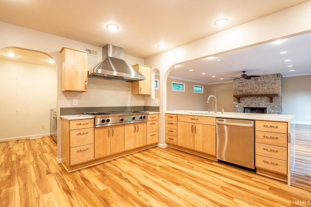 kitchen with light brown cabinets, stainless steel appliances, sink, light hardwood / wood-style floors, and wall chimney range hood