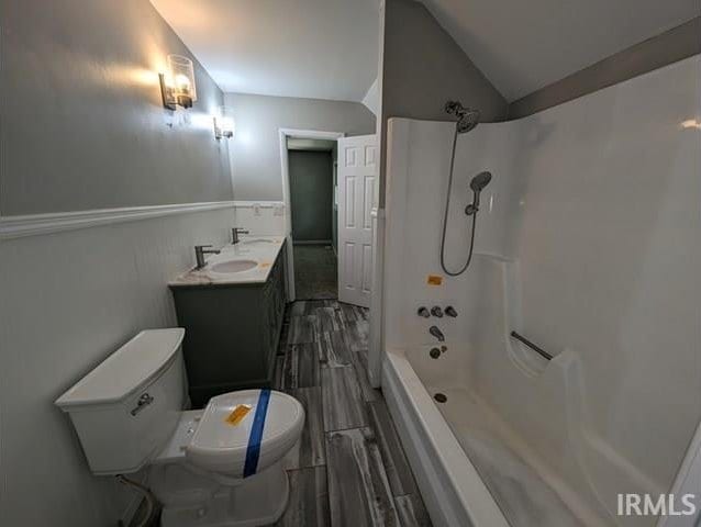 full bathroom featuring shower / bath combination, toilet, vaulted ceiling, and vanity