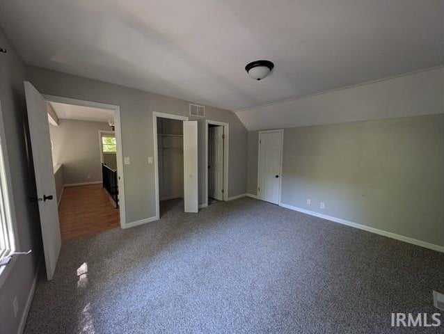 unfurnished bedroom featuring carpet flooring, two closets, visible vents, and baseboards
