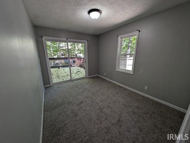 spare room featuring a textured ceiling, carpet flooring, and baseboards