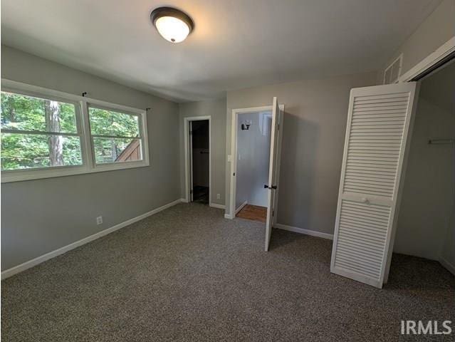 unfurnished bedroom with dark colored carpet and a closet