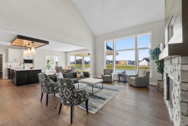 living room featuring a water view, a fireplace, high vaulted ceiling, and dark hardwood / wood-style flooring