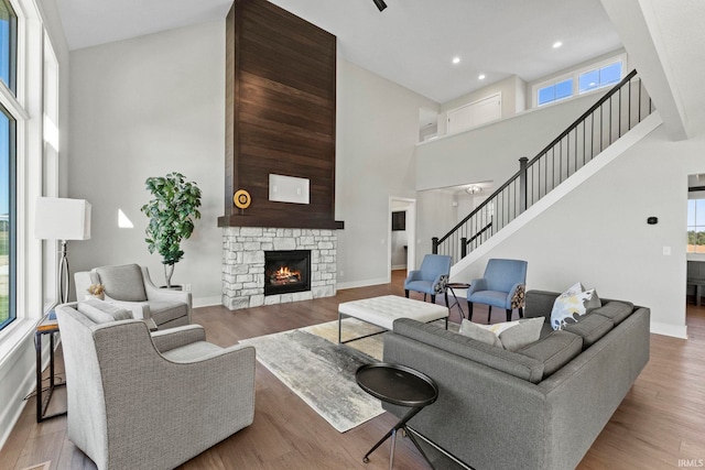 living room featuring a fireplace, a towering ceiling, and light hardwood / wood-style floors