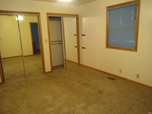 unfurnished bedroom featuring carpet flooring and two closets