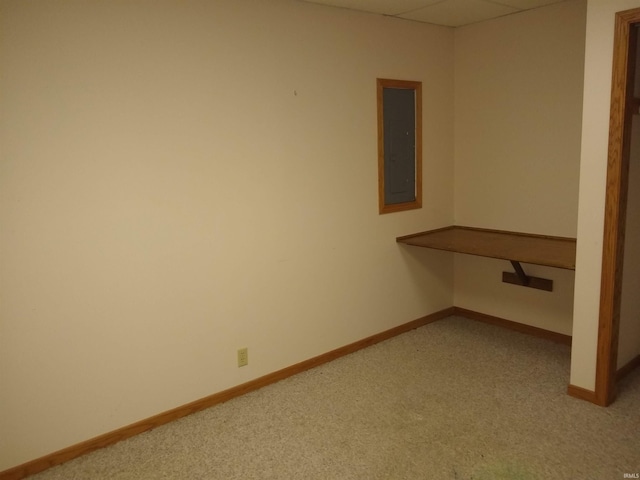 carpeted empty room with a drop ceiling and electric panel