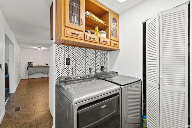 washroom featuring washing machine and clothes dryer, cabinets, and dark tile patterned flooring