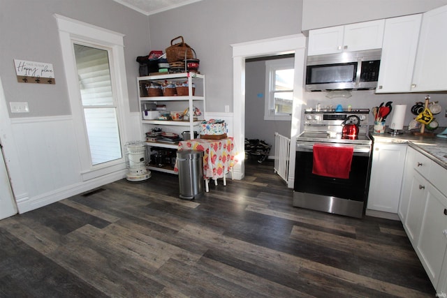 kitchen with ornamental molding, dark wood-type flooring, stainless steel appliances, and white cabinets