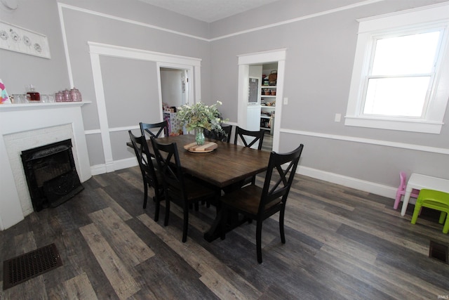 dining space featuring a fireplace and dark wood-type flooring