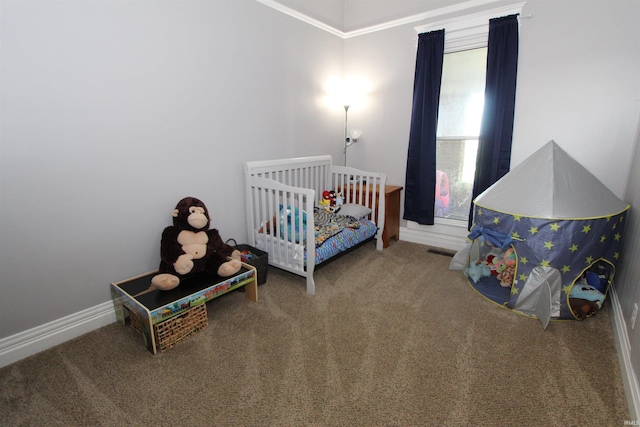 carpeted bedroom with ornamental molding and a nursery area