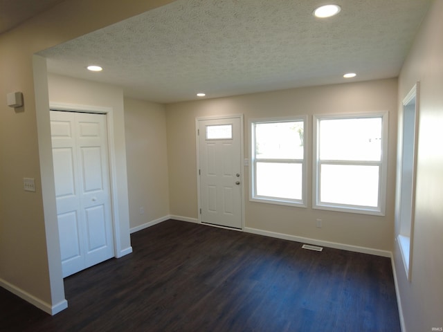 foyer with dark wood-type flooring and a textured ceiling