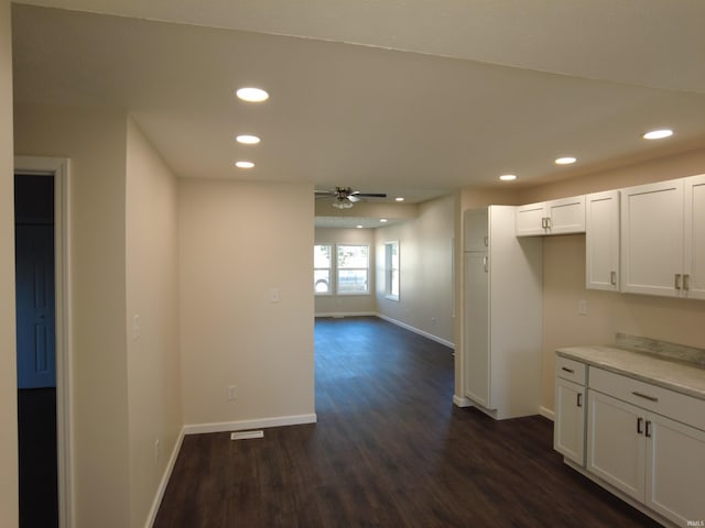 kitchen with dark wood-type flooring, ceiling fan, and white cabinetry