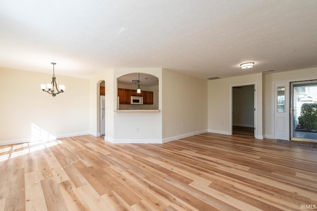 unfurnished living room featuring light hardwood / wood-style flooring and a chandelier