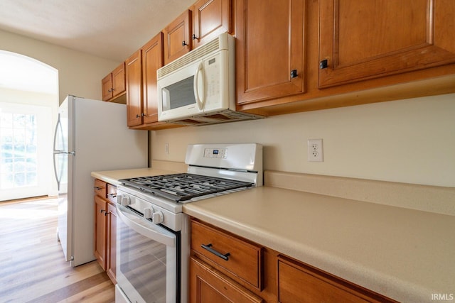 kitchen with white appliances and light hardwood / wood-style floors