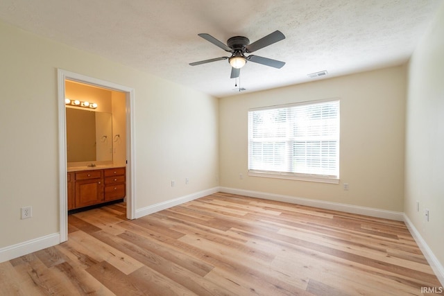 unfurnished bedroom featuring light hardwood / wood-style flooring, connected bathroom, a textured ceiling, and ceiling fan