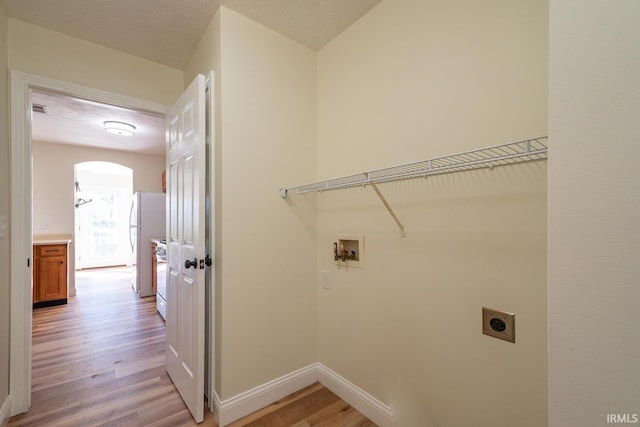 laundry area featuring light wood-type flooring, hookup for an electric dryer, washer hookup, and a textured ceiling