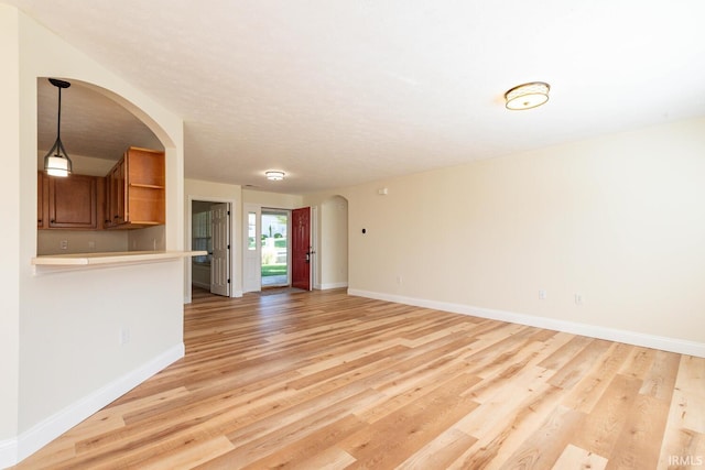 unfurnished living room with light hardwood / wood-style flooring and a textured ceiling