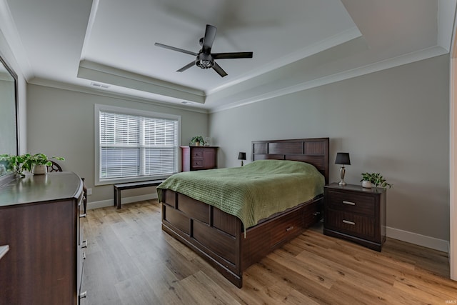 bedroom featuring light hardwood / wood-style flooring, ornamental molding, a raised ceiling, and ceiling fan