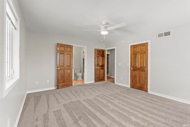 unfurnished bedroom featuring ceiling fan, light colored carpet, and ensuite bathroom