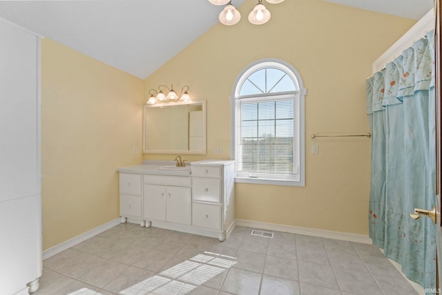 bathroom featuring tile patterned flooring, vaulted ceiling, and vanity