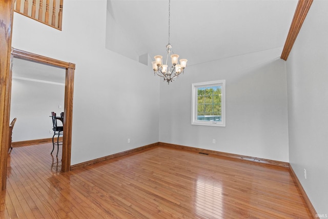 empty room with crown molding, an inviting chandelier, and light hardwood / wood-style flooring