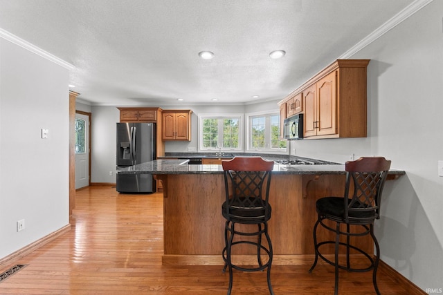 kitchen featuring kitchen peninsula, crown molding, light hardwood / wood-style flooring, a kitchen breakfast bar, and stainless steel refrigerator with ice dispenser