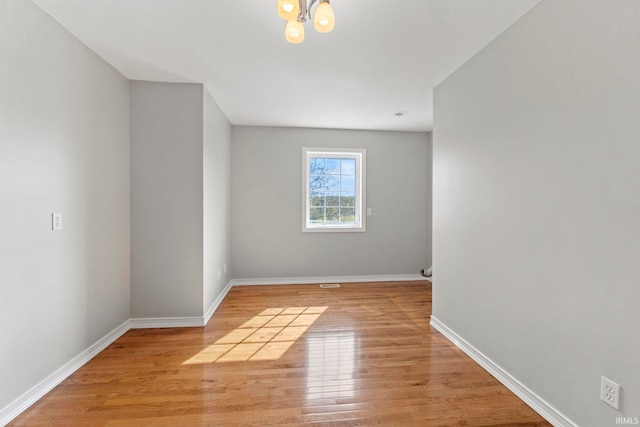 spare room with a chandelier and light hardwood / wood-style flooring