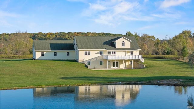 back of property with a yard and a water view