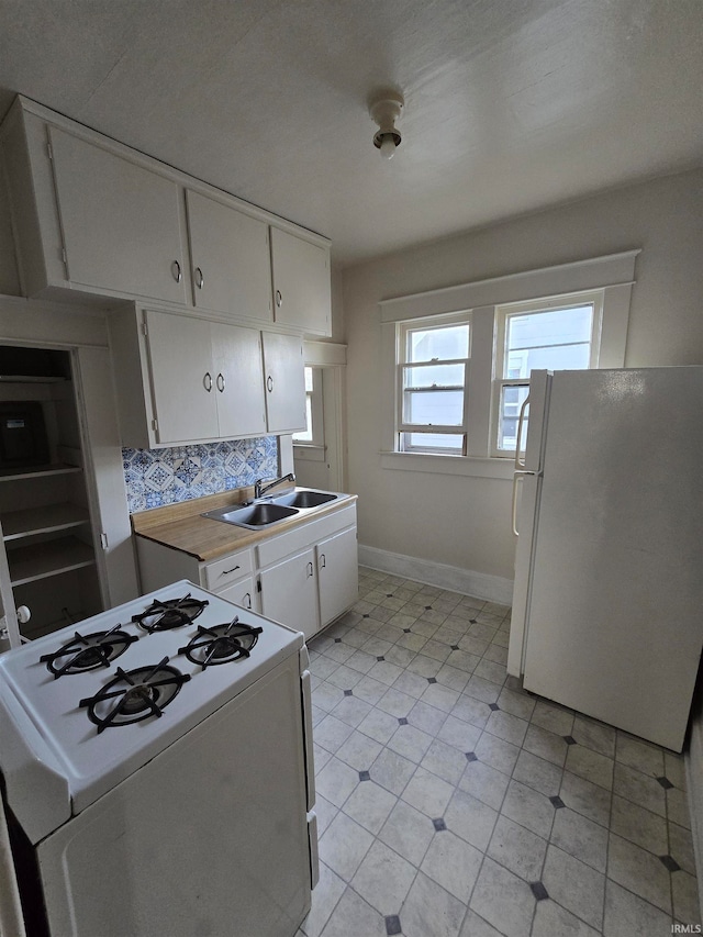 kitchen featuring decorative backsplash, white appliances, sink, and white cabinets