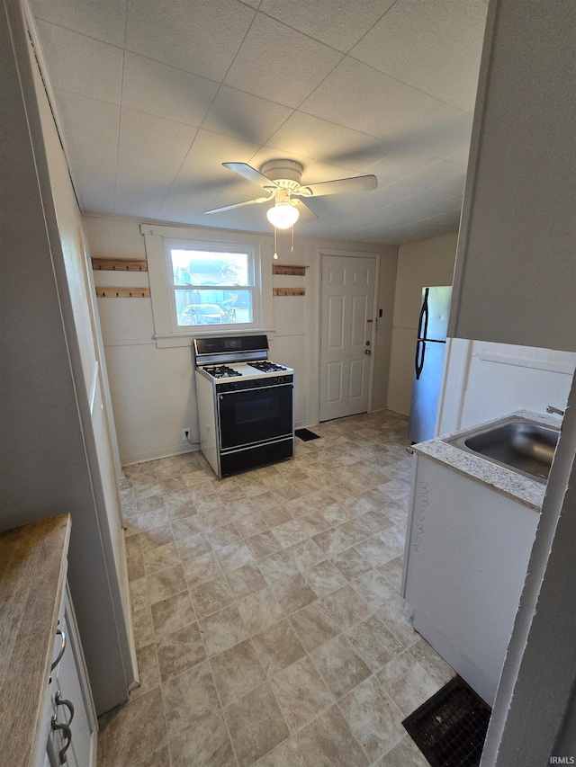 kitchen with range with gas cooktop, sink, white fridge, and ceiling fan