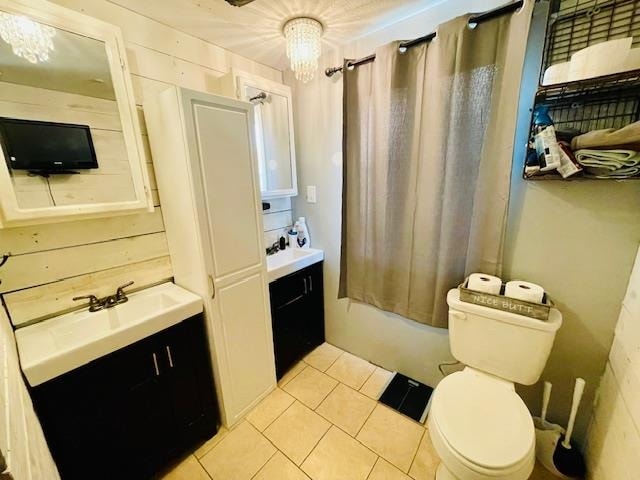 full bathroom featuring tile patterned flooring, a chandelier, toilet, shower / bath combo with shower curtain, and vanity