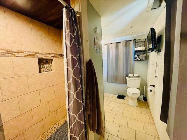 bathroom with tile patterned floors, walk in shower, and toilet