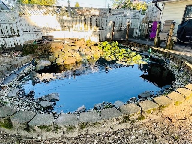 view of swimming pool featuring area for grilling and a garden pond